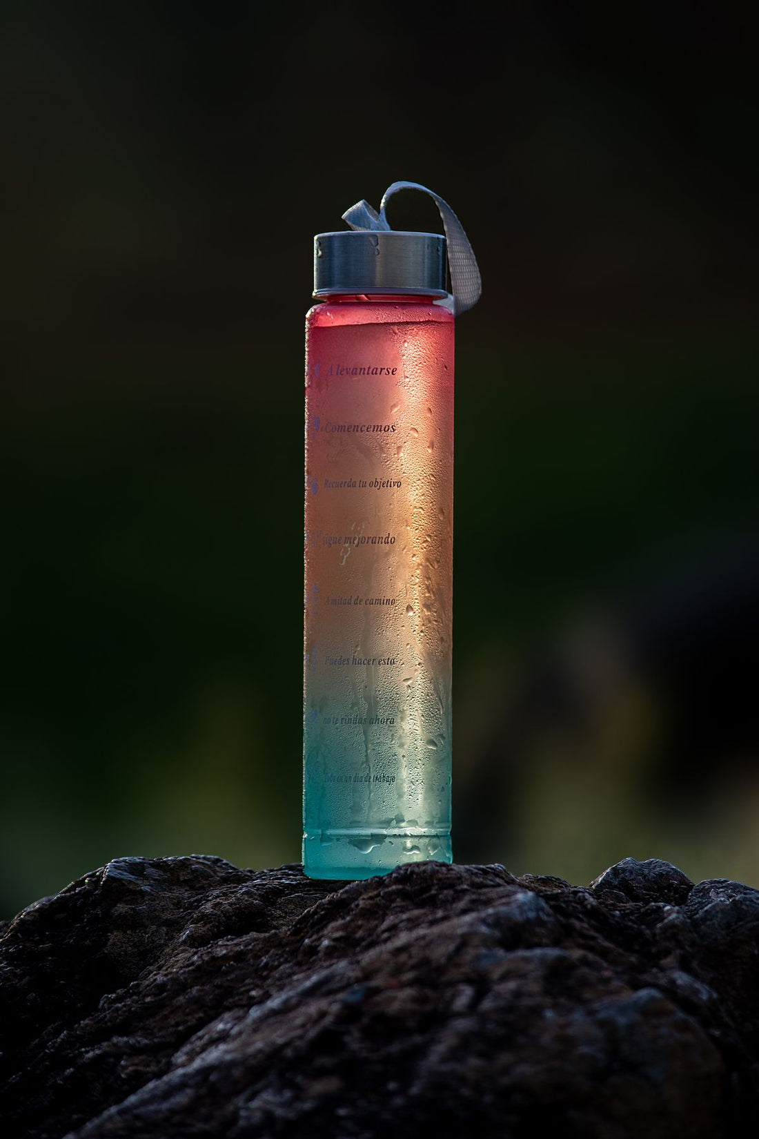 colorful gradient water bottle with condensation droplets outdoors on a summer day
