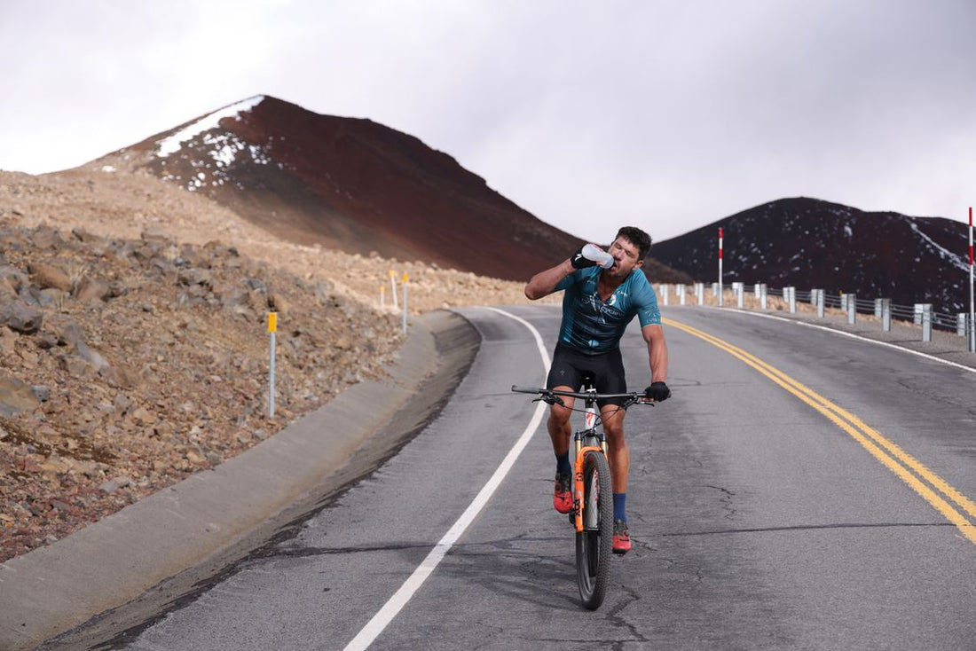 cyclist drinking water from a bottle while riding on a mountain road