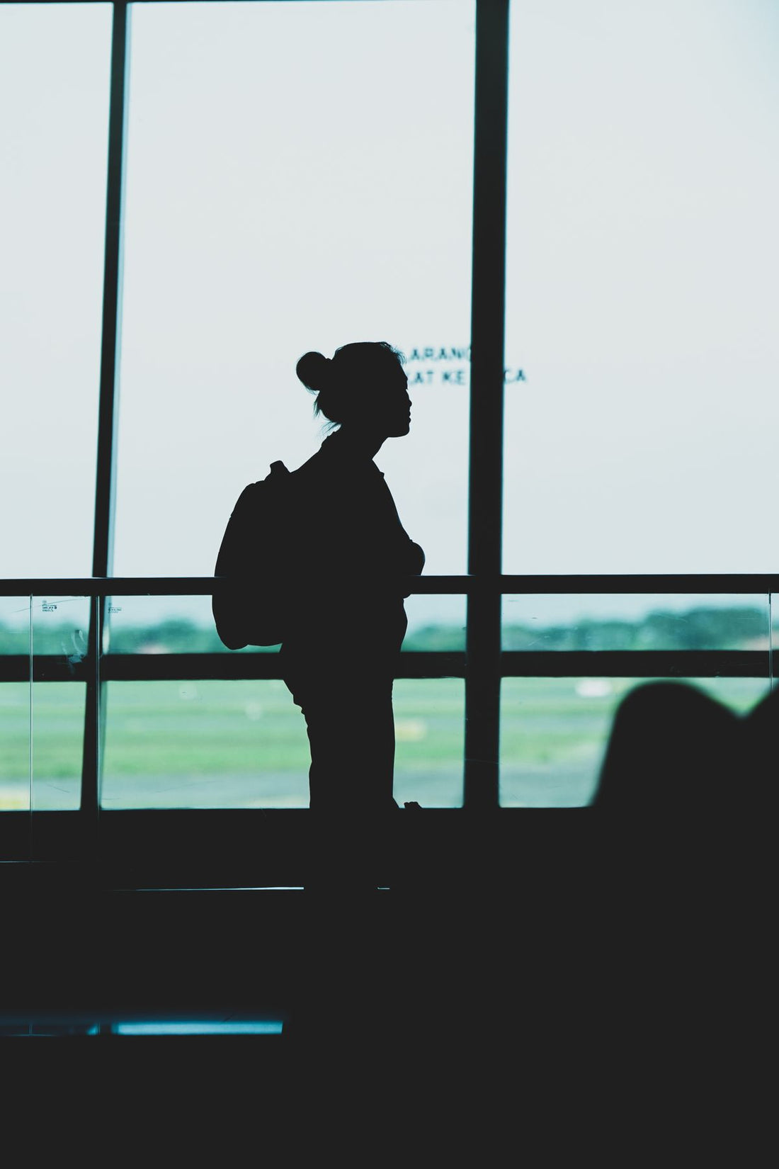 traveler with backpack standing at airport terminal window before a long flight
