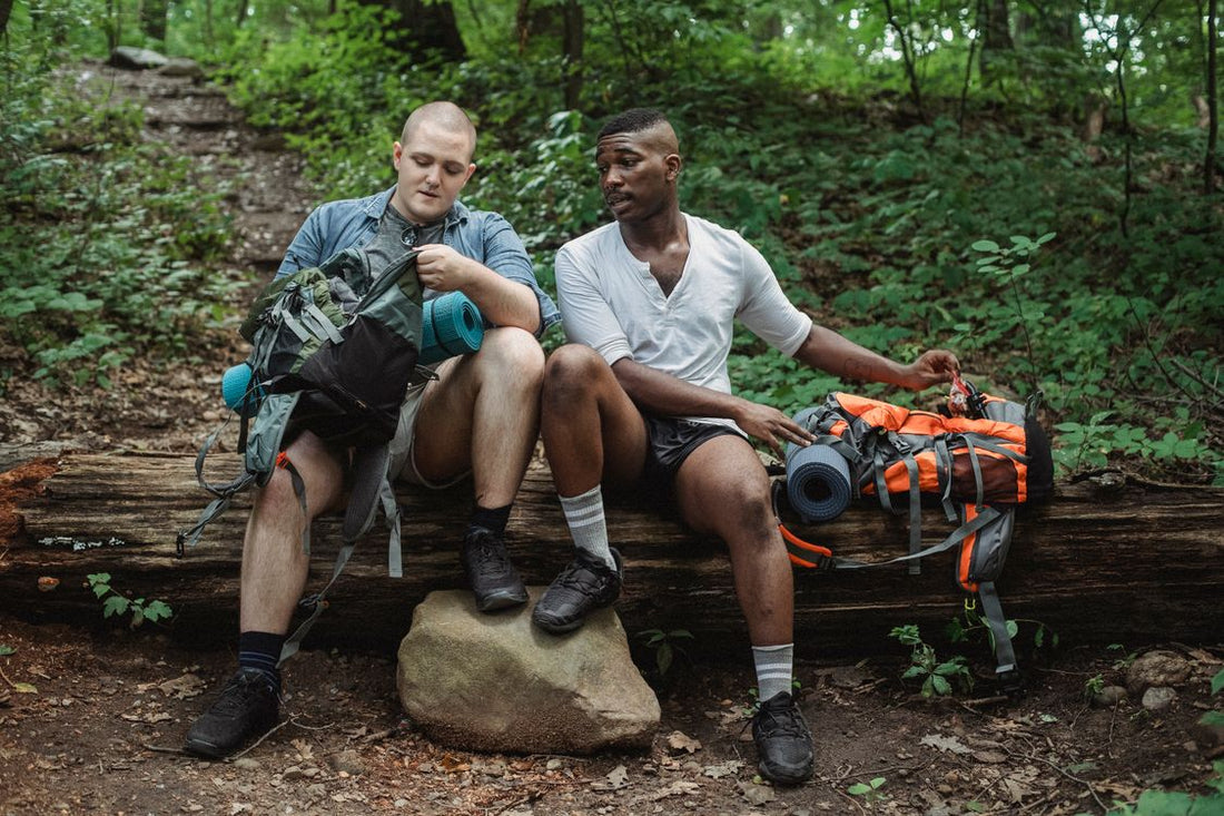 two hikers resting with backpacks on a forest trail during a hiking break