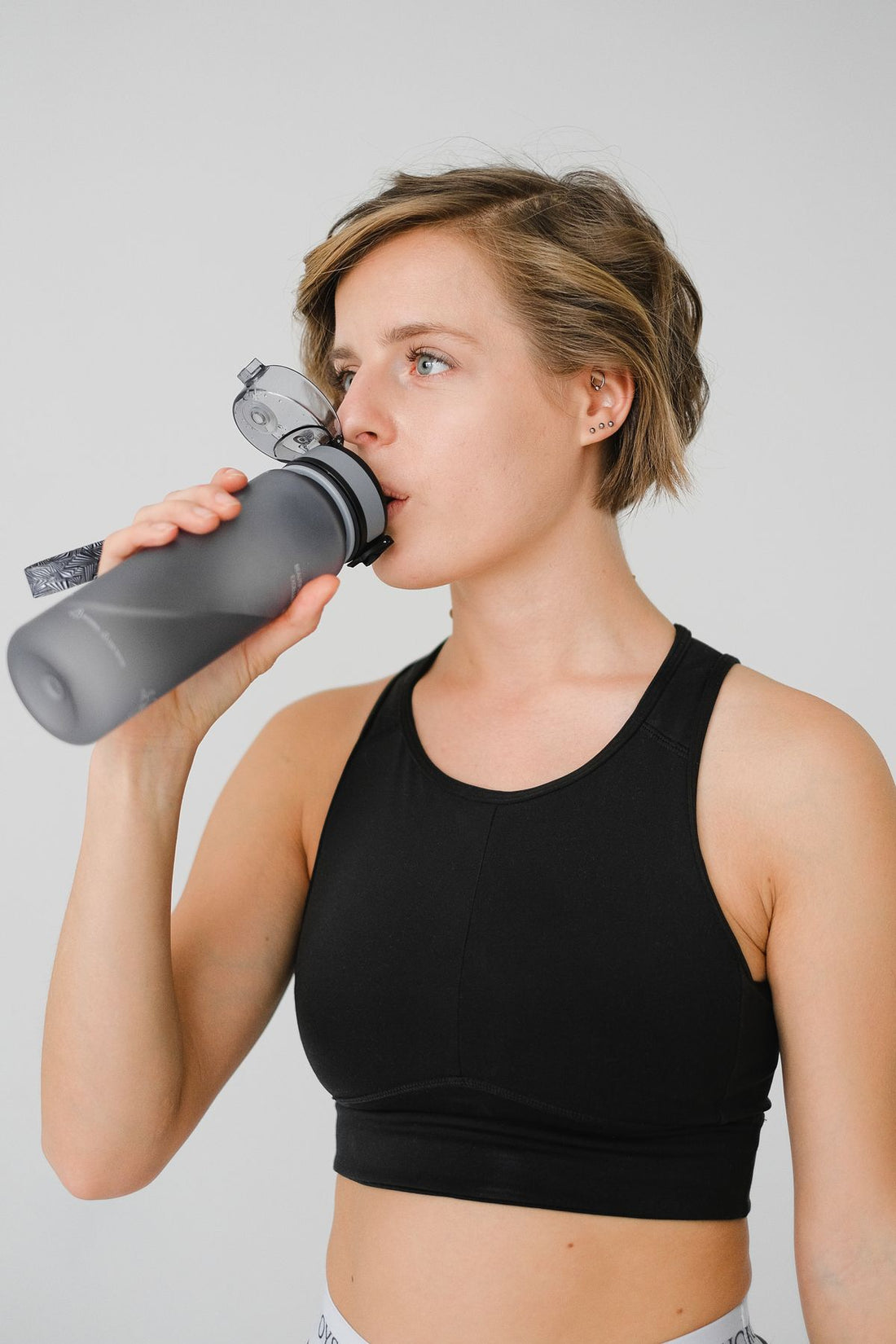 woman drinking water from a reusable water bottle during a workout