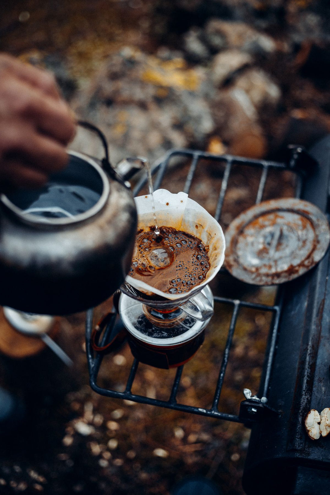 pouring hot water over pour-over coffee filter at a campsite before hiking