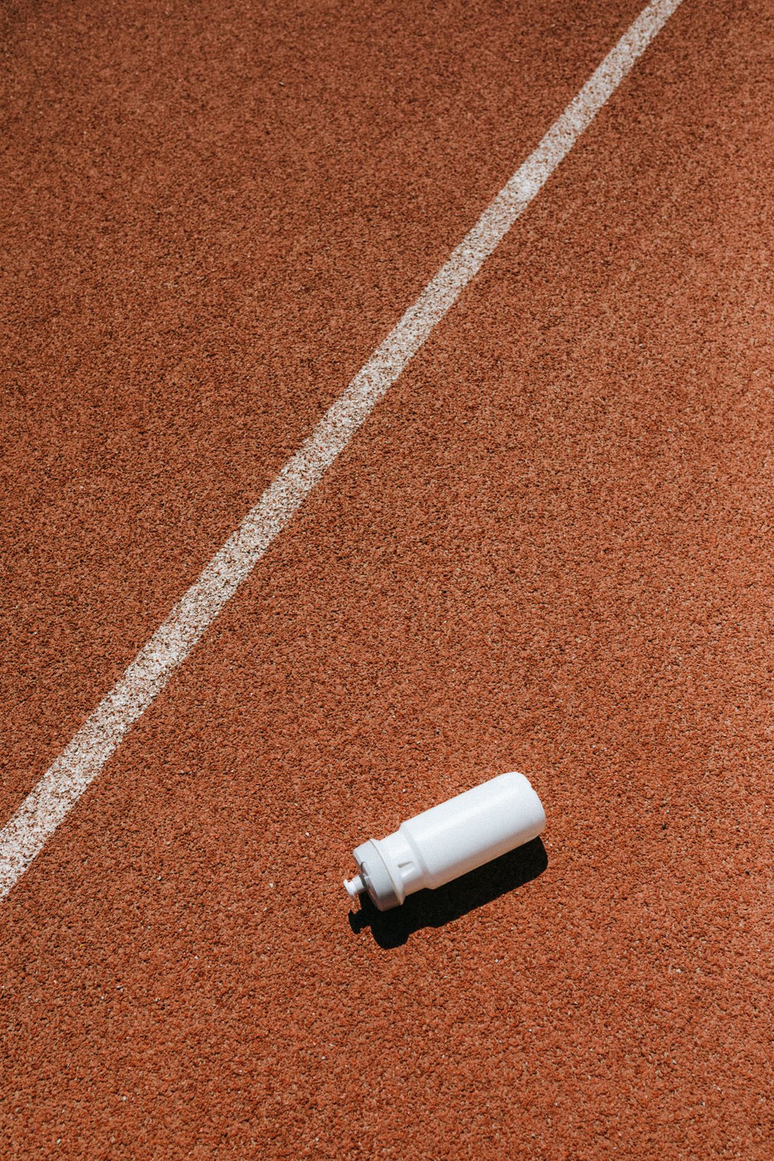 runner cooling down with a towel and water bottle on a sunny trail after a run, electrolytes vs water hydration for runners