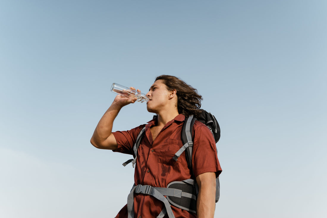 hiker drinking fresh water from a hydration reservoir on a forest trail