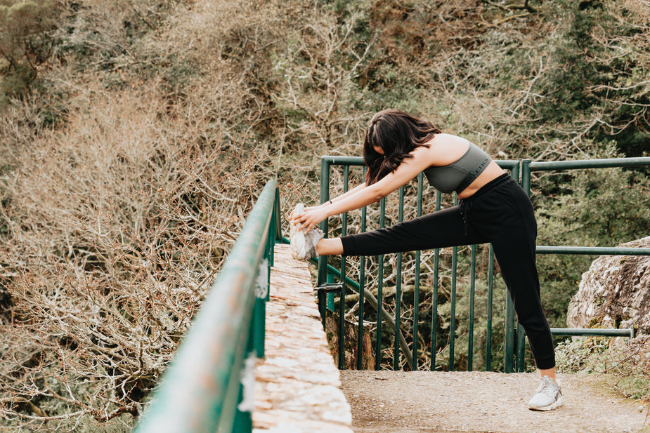 hiker stretching her leg outdoors before a hike to prevent leg cramps